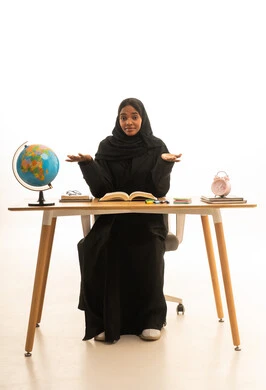 Expressions of ignorance, the arrival of exam and study time, the concept of excellence and diligence, the concept of research and exploration around the world, a portrait of a Gulf Arab Saudi student wearing an abaya and hijab sitting at a table in front of a globe model and books, white background.