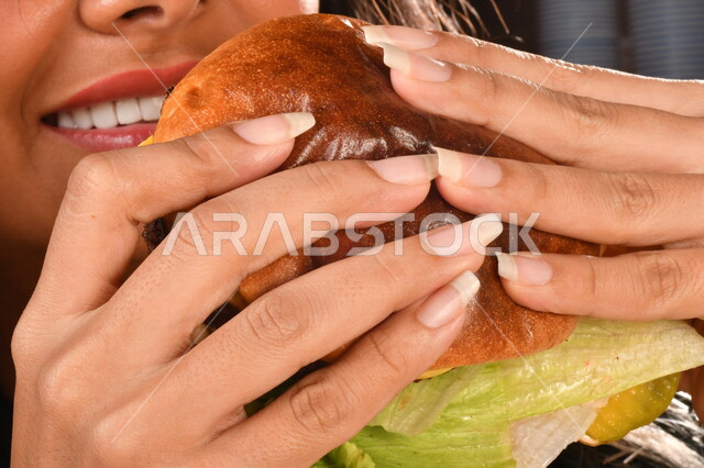  ساندويش البرجر بطبقات اللحم والخس مع الجبنه الذائبه,  إمرأه عربيه سعوديه خليجيه تتناول البرجر, الاستمتاع باكل البرجر, مأكولات سريعه, اضرار الاكثار من  تناول الوجبات السريعه