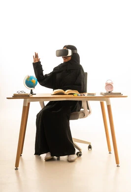 استخدام التكنولوجيا والتقنيات الحديثة، تحديد هدف معين ، قدوم وقت الامتحانات والمذاكرات، مفهوم البحث والاستكشاف حول العالم, بورتريه لطالبة عربية خليجية سعودية ترتدي العباءة والحجاب ونظارات الفى ار تجلس على الطاولة امام مجسم الكرة الارضية والكتب ، خلفية بيضاء