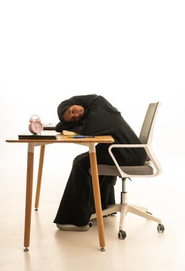 Expressions of drowsiness and the need for sleep, reviewing daily lessons, the concept of research and exploration around the world, a portrait of a Gulf Arab Saudi student wearing an abaya and hijab sitting at a table in front of a globe model and books, with a white background.