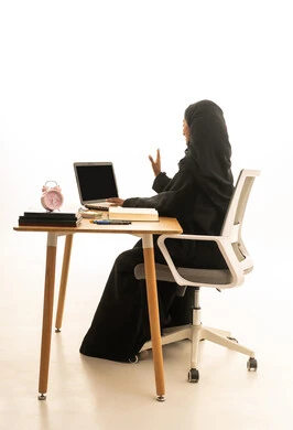 The concept of excellence and diligence, the use of technology and modern techniques, the arrival of exam time and study sessions, a portrait of a Gulf Arab Saudi student wearing an abaya and hijab sitting at a table in front of a globe model, books, and a laptop, with a white background.