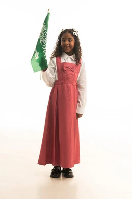 الإحتفال وإحياء ذكرى اليوم الوطني السعودي في المدارس، بورتريه لطالبه عربية خليجية سعودية ترتدي الزي المدرسي والحقيبة المدرسية، تلميذه مجتهدة ترتدي الزي المدرسي الوردي تحمل بيدها علم المملكة العربية السعودية، خلفية بيضاء.