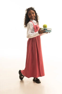 الجد والاجتهاد للوصول إلى النجاح، جودة التعليم في مدارس المملكة العربية السعودية، العودة الى المدارس، بورتريه لطالبة عربيه خليجيه سعودية مبتسمه ترتدي الزي المدرسي تحمل صندوق الطعام مع تفاحة خضراء، صورة لكامل الجسم، خلفية بيضاء