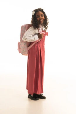 موسم العوده للمدارس, التجهيز لبداية العام الدراسي, بورتريه من الجانب لطالبة عربية خليجية سعودية ترتدي اليونيفورم المدرسي تحمل الحقيبة المدرسية, الرغبة في طلب العلم، تلميذه سعودية تنظر الى الكاميرا بتعابير السرور, الطول الكامل للجسم، خلفية بيضاء