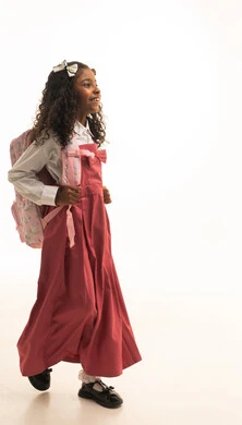 بتعابير السرور والحماس الذهاب الى المدرسة , الرغبة في طلب العلم، التجهيز لبداية العام الدراسي, موسم العوده للمدارس, بورتريه من الجانب لطالبة عربية خليجية سعودية ترتدي اليونيفورم المدرسي تحمل الحقيبة المدرسية,  الطول الكامل للجسم، خلفية بيضاء