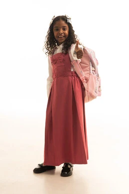 Raising the thumb with gestures of admiration, the desire for knowledge, preparing for the start of the school year, the back-to-school season, a side portrait of a Saudi Gulf Arab student wearing a school uniform carrying a school bag, full body length, white background.