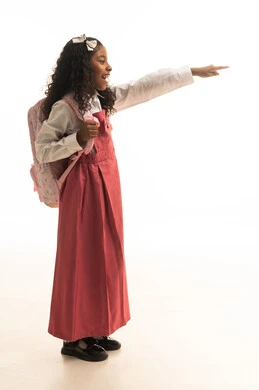 الاشارة لشيء مافي الاعلى , الرغبة في طلب العلم، التجهيز لبداية العام الدراسي, موسم العوده للمدارس, بورتريه من الجانب لطالبة عربية خليجية سعودية ترتدي اليونيفورم المدرسي تحمل الحقيبة المدرسية,  الطول الكامل للجسم، خلفية بيضاء