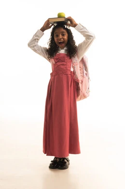 انشطة التوازن وحمل كتاب على الرأس، مفهوم القبول والاجتهاد للوصول إلى النجاح، جودة التعليم في مدارس المملكة العربية السعودية، العودة الى المدارس، بورتريه لطالبة عربيه خليجيه سعودية مبتسمه ترتدي الزي المدرسي تحمل مجموعة من الكتب، صورة لكامل الجسم، خلفية بيضاء