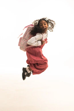 Jumping in the air with excitement, the desire for knowledge, preparing for the start of the school year, the back-to-school season, a side portrait of a Saudi Gulf Arab student wearing a school uniform carrying a school bag, full body length, white background.