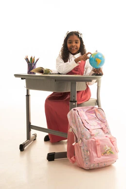 Back to school season, preparing for the new academic year, the concept of research and exploration around the world, a portrait of an Arab Gulf Omani student wearing a school uniform holding a model of the Earth, a Saudi girl looking with gestures of happiness and joy, full-body, white background.