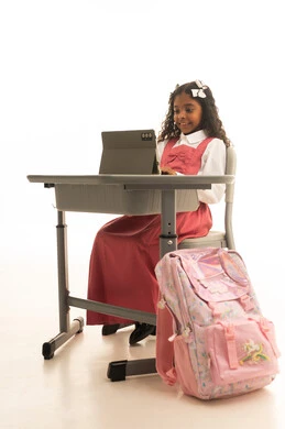 جودة أساليب التعلم الفعال، متابعة الدروس عن طريق منصات التعلم، بورتريه مقرب لطالبه عربيه خليجيه سعودية ترتدي الزي المدرسي تجلس على الطاولة المكتبيه ، بنت سعودية تقوم بحل الواجبات وتلقي المحاضرات المدرسيه عن بعد عبر التابلت، خلفية بيضاء