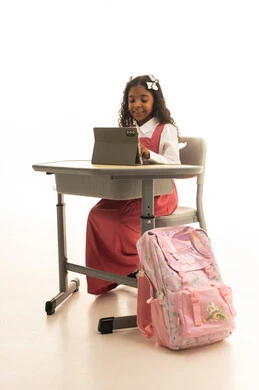 الأجهزة التقنية الحديثة بالتعلم,، متابعة الدروس عن طريق منصات التعلم، بورتريه مقرب لطالبه عربيه خليجيه سعودية ترتدي الزي المدرسي تجلس على الطاولة المكتبيه ، بنت سعودية تقوم بحل الواجبات وتلقي المحاضرات المدرسيه عن بعد عبر التابلت، خلفية بيضاء