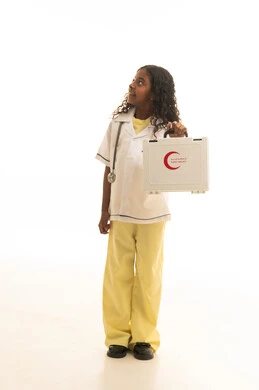 علاج أولي سريع ، التعامل مع الإصابات الشائعة و حالات الطوارئ ، بورتريه لطفلة عربية خليجية سعودية ترتدي المعطف الطبي الخاص بمهنة الطب ، تحمل بيدها حقيبة إسعافات أولية بإيماءات تدل على السعادة ، مهن مستقبلية مهمة  ، خلفية بيضاء