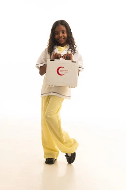 Dealing with common injuries and emergencies, a portrait of a Gulf Arab Saudi girl wearing a medical coat, holding a first aid kit in her hand with gestures indicating happiness, quick primary treatment, important future professions, white background.