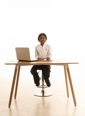 استخدام الاجهزة التقنية الحديثة،تدوين نتائج الفحوصات، الهدف والطموح المستقبلي، بورتريه مقرب لبنت  عربية خليجية سعودية  ترتدي المعطف الأبيض تجلس خلف المكتب تعمل على الحاسوب المحمول، فتاة سعودية  تقوم بإعداد التقارير، صورة لكامل الجسم، خلفية بيضاء