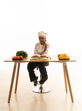 فن الطبخ وتحضير الطعام,متابعة الخطوات اللازمة من كتاب وصفات الطهي الشهي,  بورتريه لطفلة عربية خليجيه سعودية ترتدي لباس الطباخ الكامل مع القبعة البيضاء تقرأ الكتاب بإيماءات السعادة, خلفية بيضاء