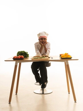 متابعة الخطوات اللازمة من كتاب وصفات الطهي الشهي, فن الطبخ وتحضير الطعام, بورتريه لطفلة عربية خليجيه سعودية ترتدي لباس الطباخ الكامل مع القبعة البيضاء تقرأ الكتاب بإيماءات السعادة, خلفية بيضاء