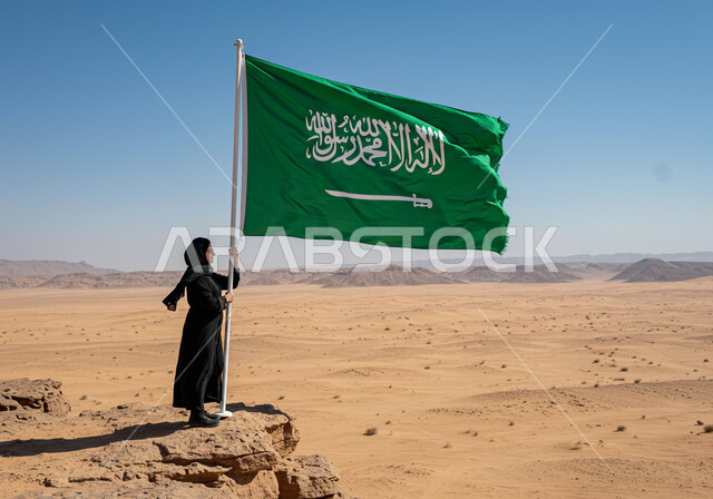 راية التوحيد وشعار الوطن، الاحتفال بالمناسبات والأعياد الوطنية، يوم العلم 11 مارس، اليوم الوطني السعودي 23 سبتمبر، إمرأة عربية خليجية سعودية ترتدي الحجاب والعباءة تعتز بالوطن، رفع علم المملكة العربية السعودية وسط الصحراء