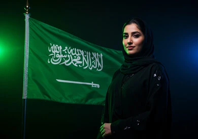 Flag Day, March 11, national celebrations and occasions in the Kingdom of Saudi Arabia, looking at the camera with expressions of joy and pride in belonging to the homeland, a smiling Saudi Arabian Gulf woman wearing a hijab and abaya celebrating Saudi National Day, September 23