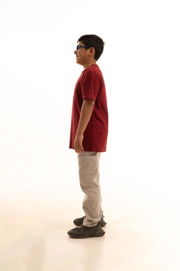 الاناقة و الاهتمام بالمظهر الخارجي, الرجولة  منذ الصغروالقوة والثقة بالنفس،الوقوف باستقامة وثبات، بورتريه جانبي لولد عربي خليجي سعودي مبتسم يرتدي الزي الكاجوال سروال وفانيلا حمراء ينظر الى الكاميرا بتعابير الفرح والسرور، صورة الجسم بالطول الكامل، خلفية بيضاء