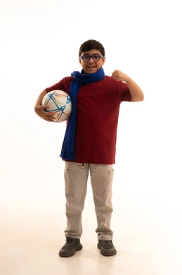 النظر إلى الكاميرا بروح العزيمة على الانتصار، الحماس للمنافسة وتعابير الفرح والسرور، تشجيع الفريق السعودي، جاهز للتحدي والفوز، بورتريه لولد عربي خليجي سعودي يرتدي الزي الكاجوال ووشاح أزرق يرفع قبضة يده ويحمل كرة , صورة الجسم بالطول الكامل, خلفية بيضاء