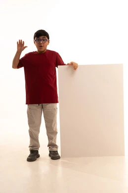 النظر إلى الكاميرا بإيماءات الدهشة والمفاجأة،  لوح إعلاني فارغ، موك أب مستطيل أبيض, استخدام لوحات تعبيرية توضيحية، بورتريه لولد عربي خليجي سعودي مبتسم يرتدي الزي الكاجوال سروال وفانيلا حمراء يقف بإستقامة ويمسك بيده لوحة مربعة بيضاء، الجسم بالطول الكامل، خلفية بيضاء