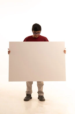 موك أب مربع أبيض, النظر إلى الكاميرا بإيماءات السرور، لوح إعلاني فارغ، استخدام لوحات تعبيرية توضيحية، بورتريه لولد عربي خليجي سعودي مبتسم يرتدي الزي الكاجوال سروال وفانيلا حمراء يقف بإستقامة ويمسك بيده لوحة مربعة بيضاء، الجسم بالطول الكامل، خلفية بيضاء