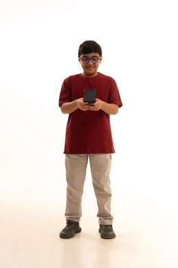الدردشة والتواصل مع الاهل والاصدقاء عبر الجوال،  استخدام جهاز تقني حديث ومتطور، بورتريه لولد عربي خليجي سعودي يرتدي الزي الكاجوال سروال وفانيلا حمراء يمسك الهاتف المحمول, استخدام التكنولوجيا والتقنيات الحديثة، الجسم بالطول الكامل، خلفيه بيضاء