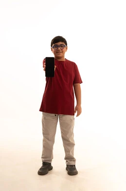 عرض خلفية سوداء على الهاتف، استخدام جهاز تقني حديث ومتطور، الدردشة والتواصل مع الاهل والاصدقاء عبر الجوال، بورتريه لولد عربي خليجي سعودي يرتدي الزي الكاجوال سروال وفانيلا حمراء يمسك الهاتف المحمول, استخدام التكنولوجيا والتقنيات الحديثة، الجسم بالطول الكامل، خلفيه بيضاء