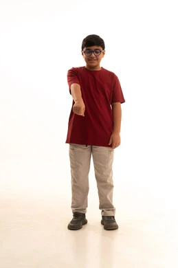 Standing straight and looking at the camera, body movements and gestures indicating pointing to someone, standing straight and looking at the camera, a portrait of an Arab Gulf Saudi boy wearing casual attire, pants and a red t-shirt, pointing with his finger forward, full-body image, white background.