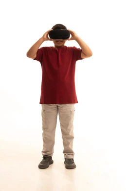 مفهوم المتعة والتسلية، التطور التقني والتكنولوجي، محاكاة العالم الخيالي والنظر الى الافلام الواقعيه،  بورتريه لولد عربي خليجي سعودي يرتدي الزي الكاجوال سروال وفانيلا حمراء ينظر من خلال نظارات ثلاثية الأبعاد (الفي ار),  الجسم بالطول الكامل، خلفيه بيضاء