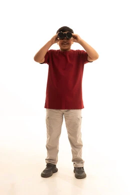 التخطيط المستقبلي للأهداف والطموحات، حب الاستكشاف والمغامرة، رؤية الاشياء البعيدة عبر المنظار، الاشارة لشيء ما باستخدام اليد ،  بورتريه لولد عربي خليجي سعودي مبتسم يرتدي الزي الكاجوال يحمل بيده المنظار ثنائي العينين، الجسم بالطول الكامل، خلفية بيضاء