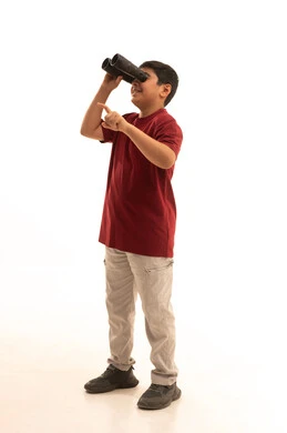 Seeing distant things through binoculars, pointing to something with the hand, future planning for goals and ambitions, a portrait of a smiling Arab Gulf Saudi boy wearing casual attire holding binoculars in his hand, a love for exploration and adventure, full-body, white background.