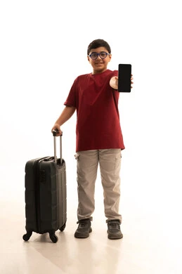 A black screen on a mobile phone, talking to friends and family before traveling, using technologies and travel applications and hotel bookings, the concept of tourism and travel, a portrait of an Arab Gulf Saudi boy wearing casual attire, red pants and a t-shirt, holding a mobile phone and a travel bag, white background.