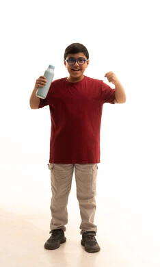 أهمية شرب الحليب عند الأطفال, إتباع نظام غذائي صحي, بورتريه لولد عربي خليجي سعودي مبتسم يرتدي الزي الكاجوال والنظارة الطبية يحمل بيده زجاجة حليب, مفهوم العناية والاهتمام بالصحة, خلفية بيضاء, جسم بالطول الكامل