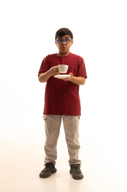 إتباع نظام غذائي صحي, أهمية شرب الحليب عند الأطفال, بورتريه لولد عربي خليجي سعودي مبتسم يرتدي الزي الكاجوال والنظارة الطبية يحمل بيده فنجان حليب, مفهوم العناية والاهتمام بالصحة, خلفية بيضاء, الجسم بالطول الكامل