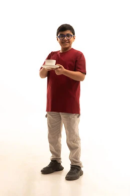 إتباع نظام غذائي صحي, أهمية شرب الحليب عند الأطفال, بورتريه لولد عربي خليجي سعودي مبتسم يرتدي الزي الكاجوال والنظارة الطبية يحمل بيده فنجان حليب, مفهوم العناية والاهتمام بالصحة, خلفية بيضاء, الجسم بالطول الكامل