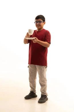 إتباع نظام غذائي صحي, أهمية شرب الحليب عند الأطفال, بورتريه لولد عربي خليجي سعودي مبتسم يرتدي الزي الكاجوال والنظارة الطبية يحمل بيده فنجان حليب, مفهوم العناية والاهتمام بالصحة, خلفية بيضاء, الجسم بالطول الكامل