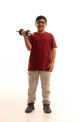 هواية ممارسة الرياضة منذ الصغر, النظر إلى الكاميرا بإيماءات السرور، رفع الأوزان الثقيلة, بورتريه لولد عربي خليجي سعودي يرتدي الزي الكاجوال يحمل بيده الأوزان الثقيلة الحديدية ( الدمبلز) , انشطة رياضية ترفيهية للأطفال, الجسم بالطول الكامل, خلفية بيضاء