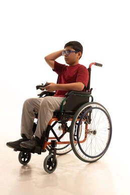 تجربة مثيرة في الأجهزة الحديثة الالكترونية، نشاطات ترفيهية لذوي الهمم، التفاعل والاندماج مع ألعاب البلايستيشن, بورتريه لولد عربي خليجي سعودي مقعد يرتدي الزي الكاجوال والنظارة الطبية يجلس على كرسي متحرك يحمل بيده عصا التحكم، خلفية بيضاء