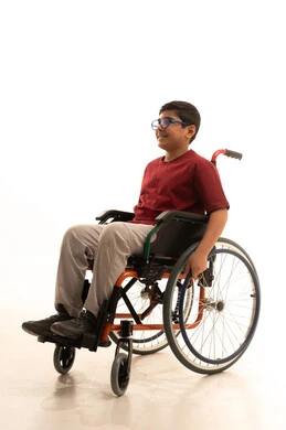 الاناقة والاهتمام بالمظهر الخارجي، ايماءات السرور والفرح، بورتريه لولد عربي خليجي سعودي من ذوي الاحتياجات الخاصة يرتدي الزي الكاجوال والنظارة الطبية يجلس على كرسي متحرك ينظر إلى شيء ما، خلفية بيضاء