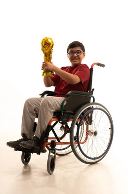 Expressions of joy and happiness, developing sports hobbies for people with disabilities, a portrait of a smiling Arab Gulf Saudi boy in a wheelchair wearing casual attire and glasses, sitting in a wheelchair holding a golden cup, raising his hand in gestures of victory and success, recreational activities for people of determination, white background.