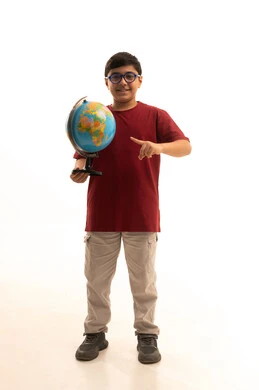Identifying the location of Arab countries on the world map, research and exploration about the universe, a portrait of a Gulf Arab Saudi boy wearing casual attire and glasses holding a globe model in his hand, the concept of trips and tourist tours, full-body, white background.