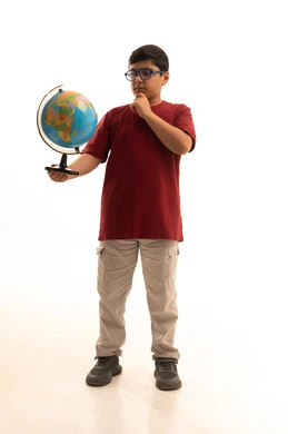 تحديد موقع الدول والبلدان العربية على خريطة العالم, البحث والاستكشاف حول الكون, بورتريه لولد عربي خليجي سعودي يرتدي الزي الكاجوال والنظارة الطبية يحمل بيده مجسم الكرة الارضية, مفهوم الرحلات والجولات السياحية, الجسم بالطول الكامل، خلفية بيضاء