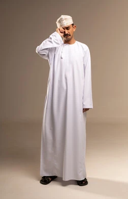 Nasal cavities and allergies, representation of authentic Arab masculinity, expressions of joy and happiness, a portrait of a Gulf Omani Arab man wearing a dishdasha and kumma, standing with his hand on his eye, the concept of caring about elegance and appearance, maintaining traditional dress, full-length body, beige background.