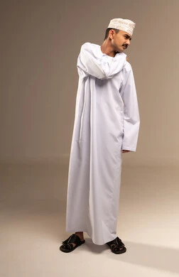 الخشونة والم في الرقبة، الذهاب للطبيب لمعالجة الاوجاع، تمثيل الرجولة العربية،  بورتريه  لرجل عربي خليجي عماني يرتدي الدشداشة والكمة، مفهوم الاهتمام بالاناقة والمظهر الخارجي، المحافظة على لبس اللباس التقليدي، الجسم بالطول الكامل، خلفية بيج