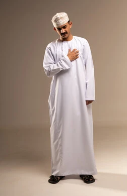 خفقان القلب وارتفاع الضغط، التعب وتحمل الالام ، الذهاب للطبيب لمعالجة الاوجاع، تمثيل الرجولة العربية،  بورتريه  لرجل عربي خليجي عماني يرتدي الدشداشة والكمة، مفهوم الاهتمام بالاناقة والمظهر الخارجي، المحافظة على لبس اللباس التقليدي، الجسم بالطول الكامل، خلفية بيج