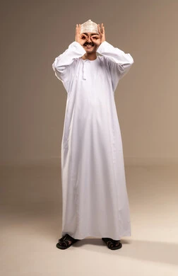 Placing the hands over the eyes like binoculars, bringing distant objects into view, achieving goals and reaching the aim, the concept of elegance and masculinity, a portrait of an Arab Gulf Omani man wearing a dishdasha and kumma standing, attention to external appearance, full-length body, beige background.