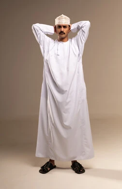 اليدين خاف الرأس على الرقبة، التوتر والضغط العالي، ألم في مقدمة الرأس بسبب التعب، تعابير التعب والارهاق، مفهوم الأناقة والرجولة، بورتريه لرجل عربي خليجي عماني يرتدي الدشداشة والكمة يقف، الاهتمام بالمظهر الخارجي، الجسم بالطول الكامل، خلفية بيج