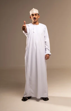 علامه الجوده تظهر عليه، رفع إصبع الإبهام للأعلى دليل على الإعجاب، ايماءات تدل على الموافقة والقبول، بورتريه لرجل عربي عماني  يرتدي الدشداشة والكمه تظهر عليه تعابير الفرح والسرور ، الرضى وعدم الرفض، الشعور بالقبول والرضا، الجسم بالطول الكامل، خلفية بيج